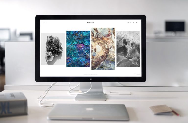 A contemporary office desk setup featuring a sleek computer monitor displaying abstract artwork