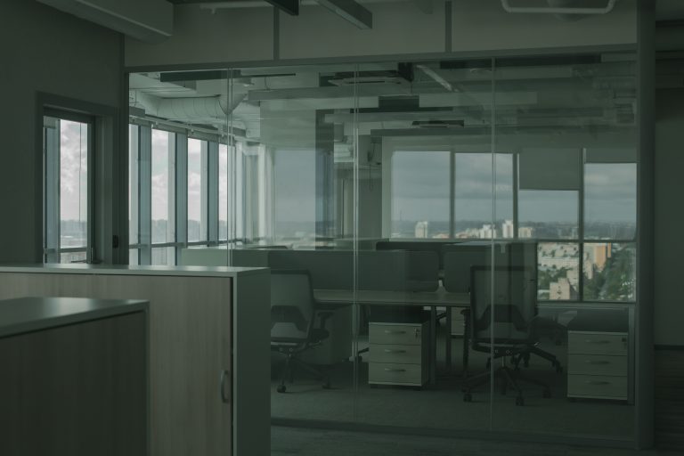 Empty office desks and chairs behind glass walls
